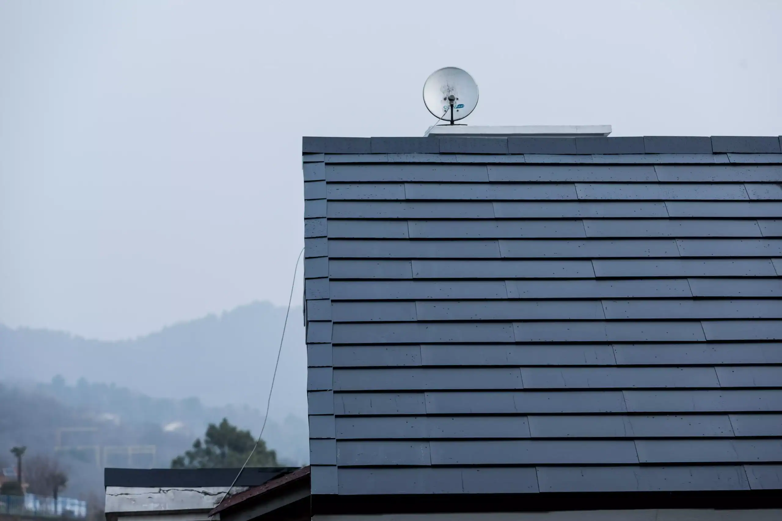 Dark integrated solar roof tiles installed on a pitched roof