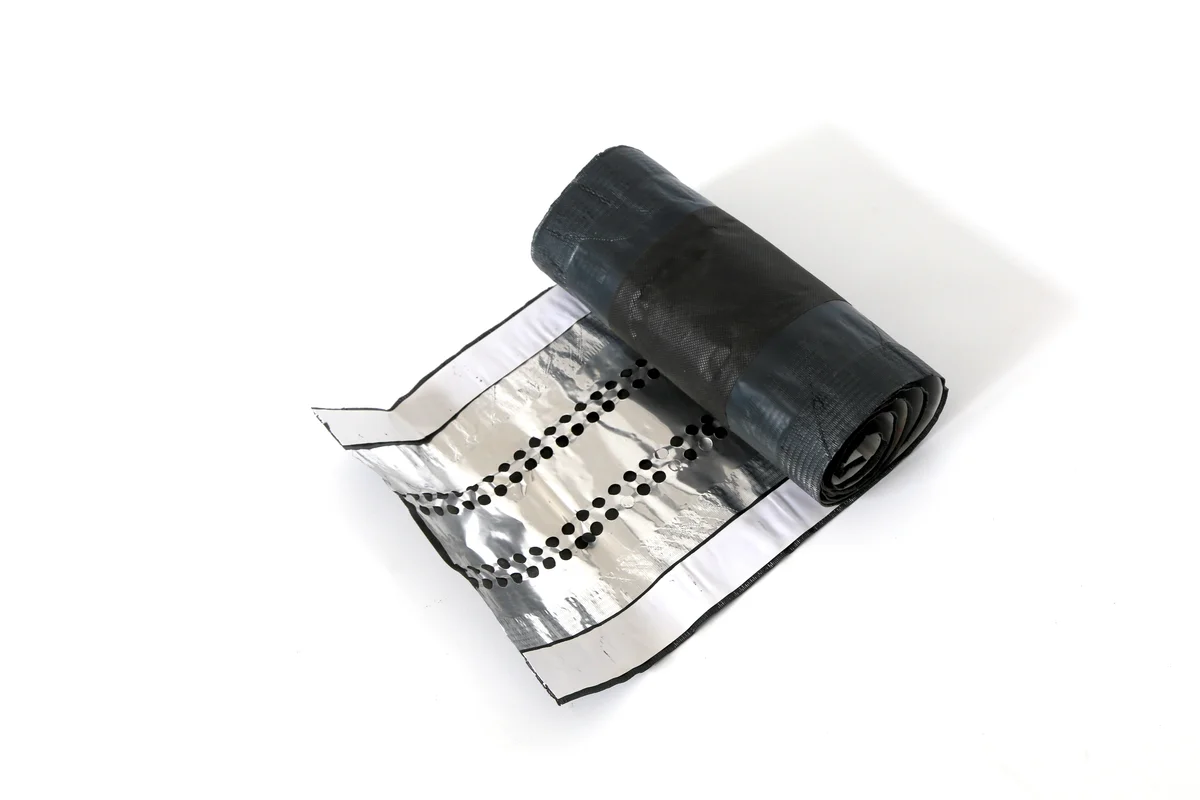 Ventilated ridge roll with metal mesh and black sealing strip for a solar roof.