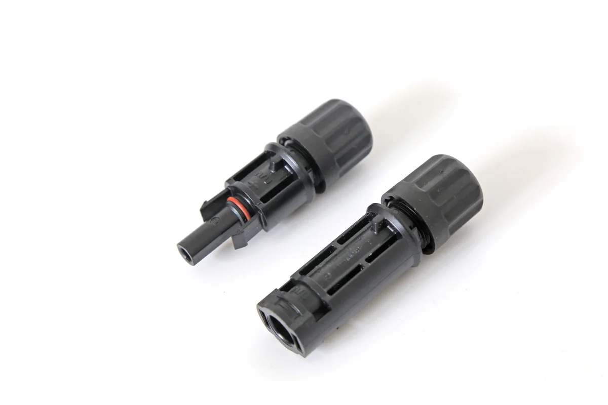 Pair of black MC4 connectors for photovoltaic cable connections in a solar roof.