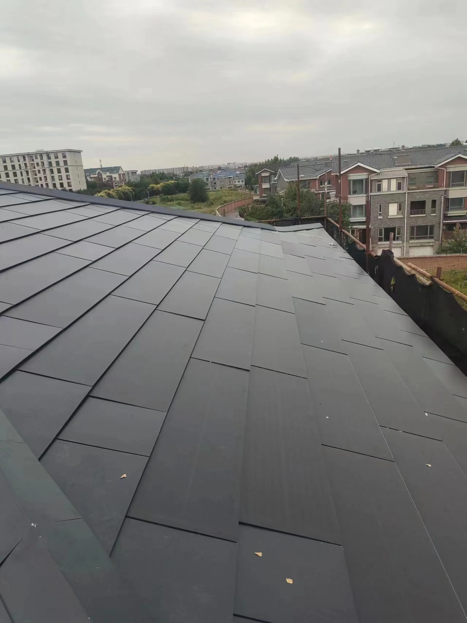 High-angle view of a staggered dark solar tile layout on a Beijing villa roof.