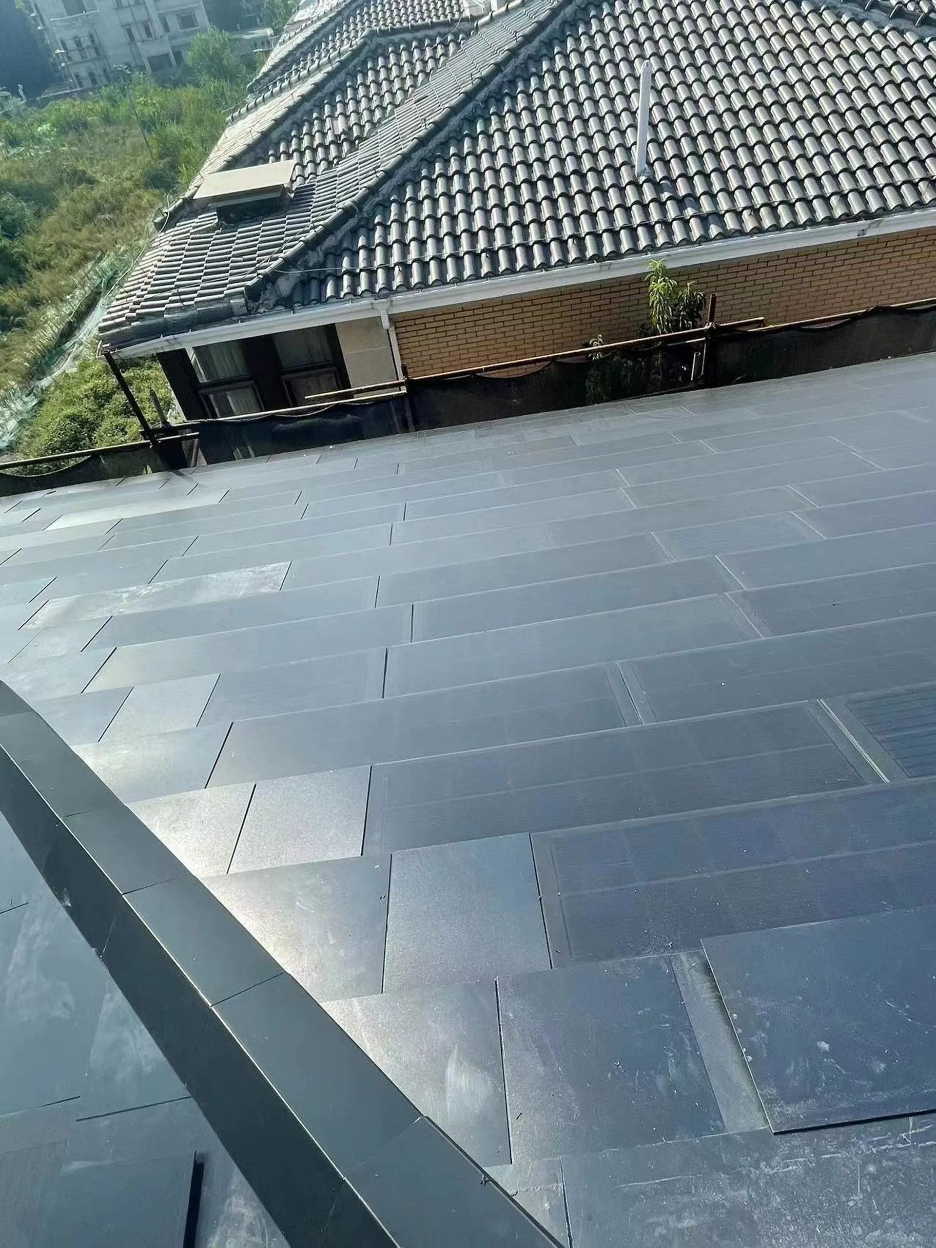 Dark Lumina Slate solar roof tiles integrated beside traditional grey roof tiles on a villa.