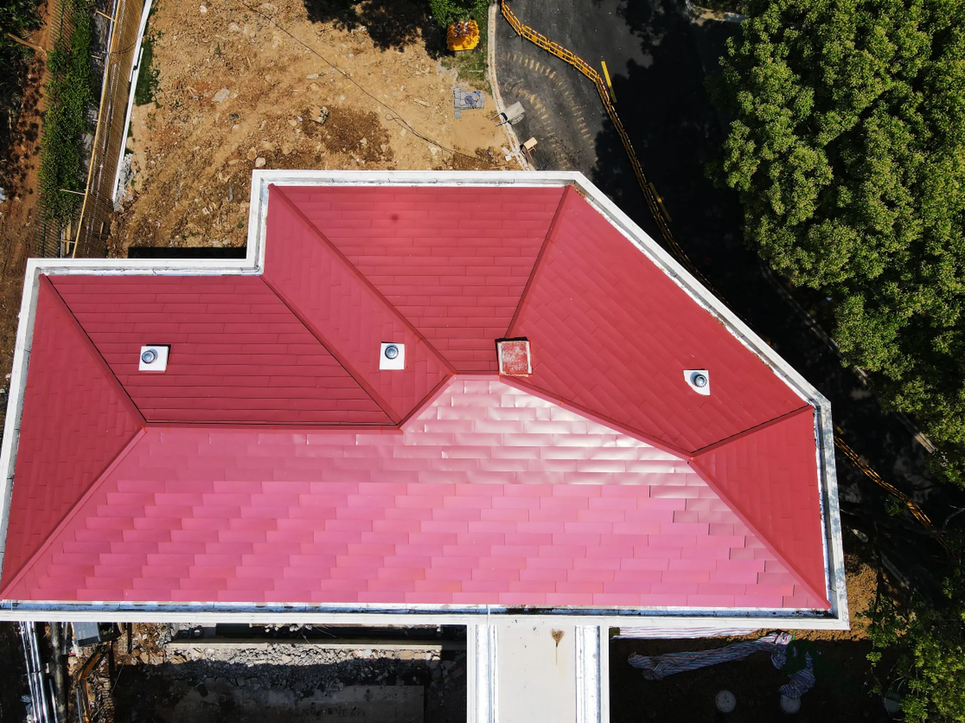 Top-down aerial view of a custom red BIPV roof, seamlessly blending active solar tiles with color-matched inactive roofing.