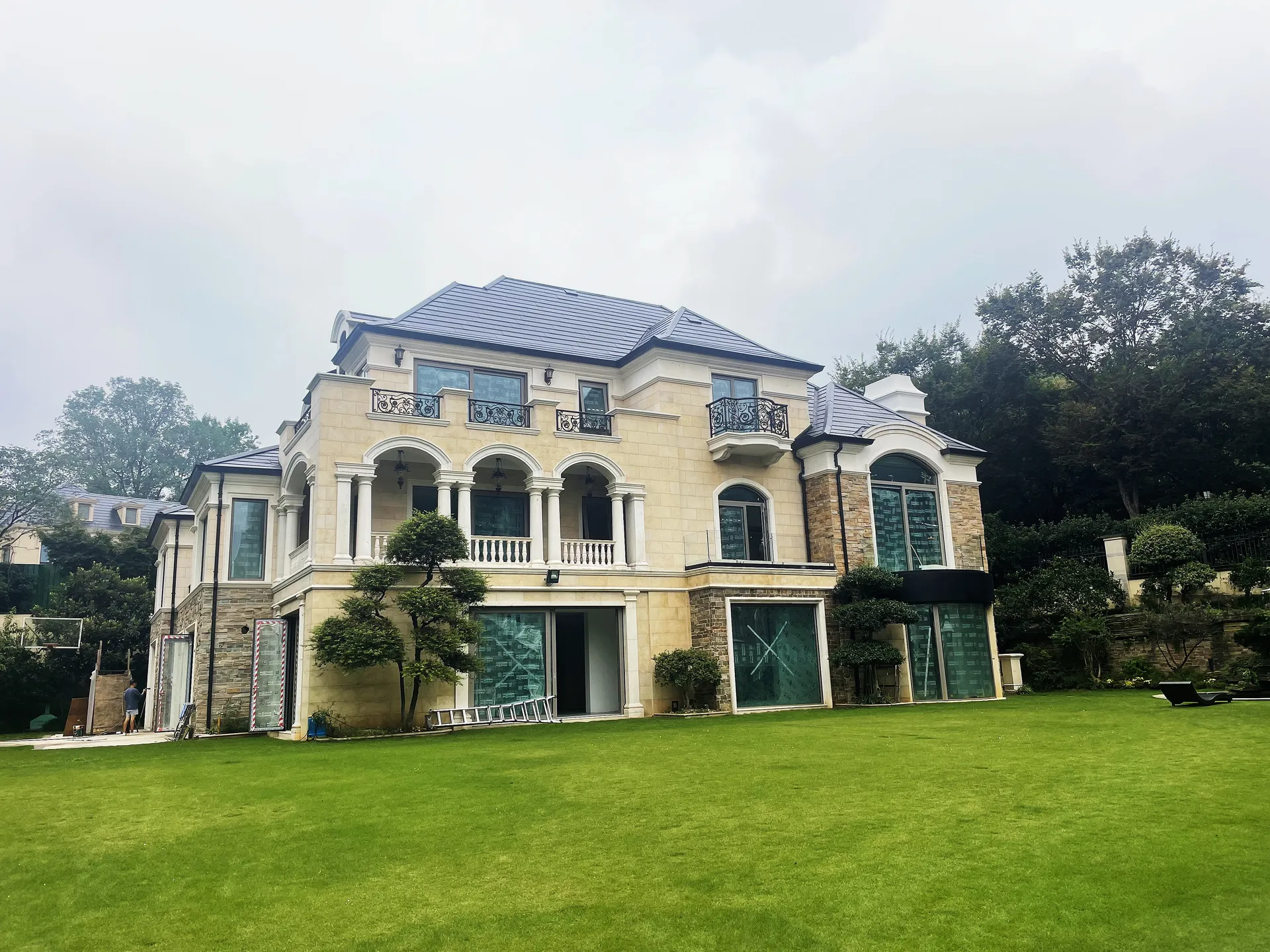 Wide exterior view of an ultra-luxury estate featuring a pristine lawn and a modern, invisible solar slate roof.
