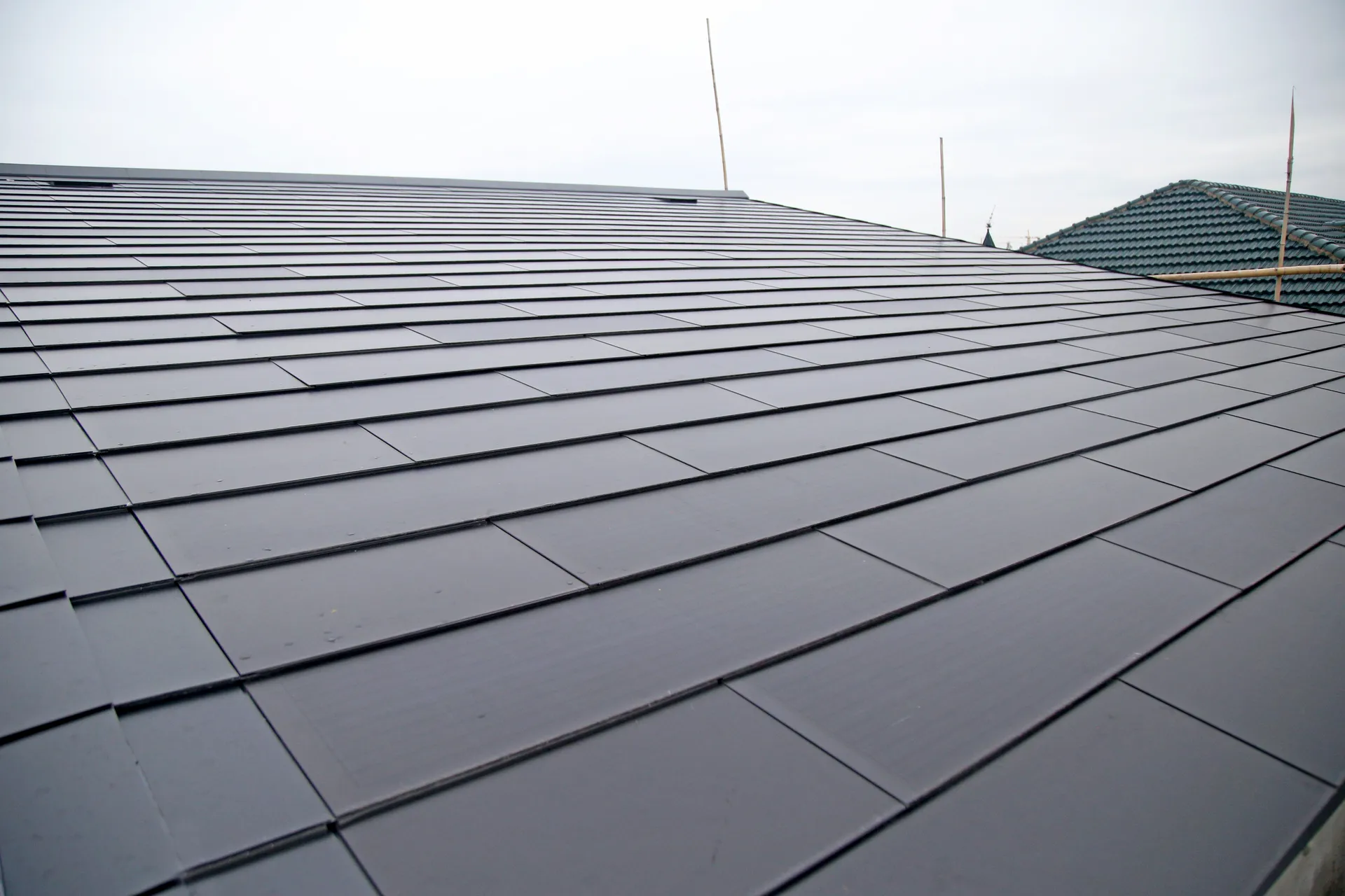 Wide view of a boutique homestay in Jiaxing featuring a modern Sunlit BIPV solar roof, contrasting with traditional green tile roofs in the background.