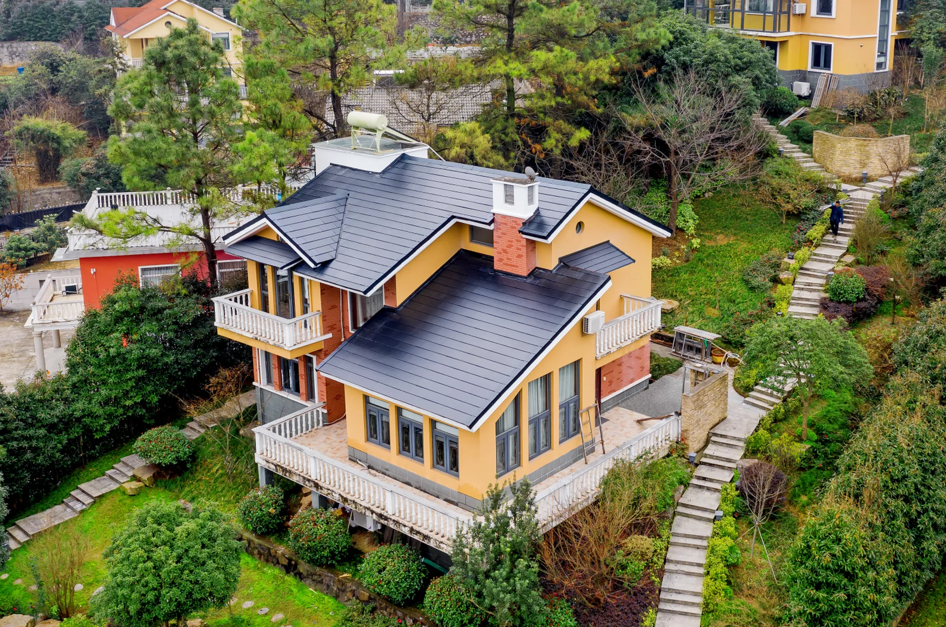 Aerial view of a vibrant yellow resort villa in Nanjing Nanshan Lake, beautifully topped with a modern dark solar roof.
