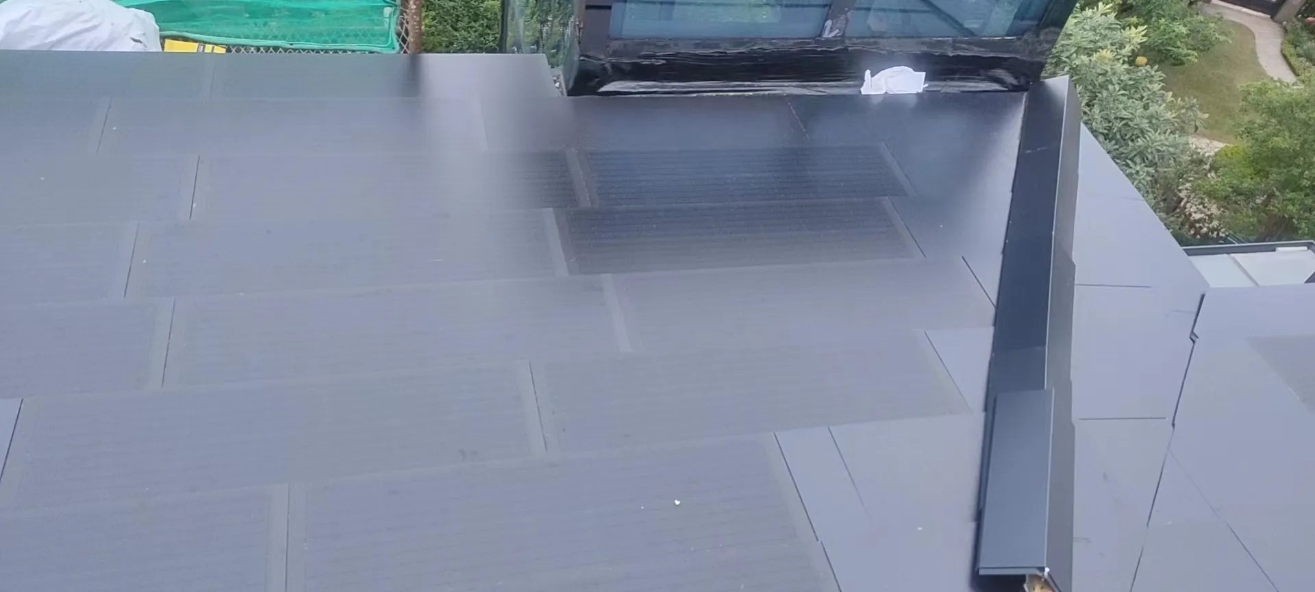 Detailed look at the custom ridge capping and modular layout of the BIPV roofing system during installation.
