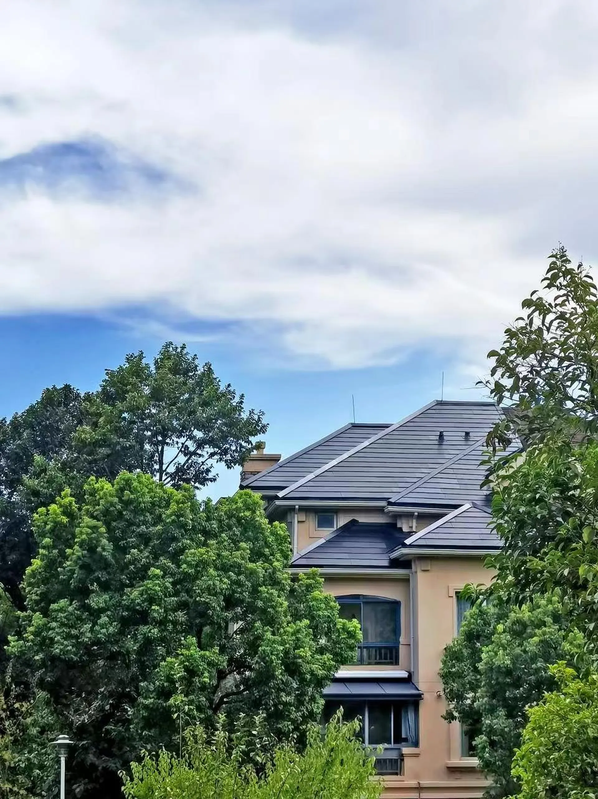 Completed Nanjing villa with a dark integrated solar roof under a blue sky.