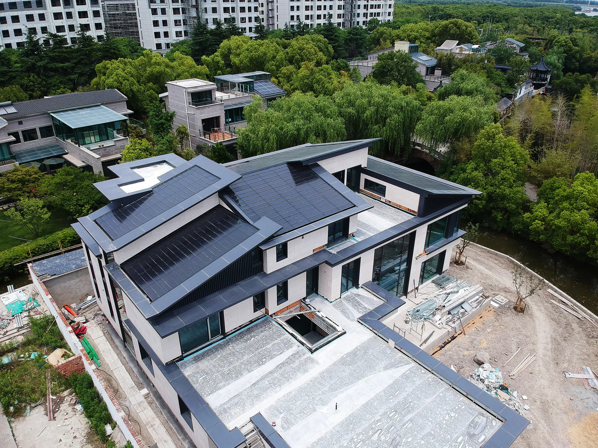 High-angle shot showing the modern solar roof harmonizing perfectly with the premium estate and surrounding natural landscape.