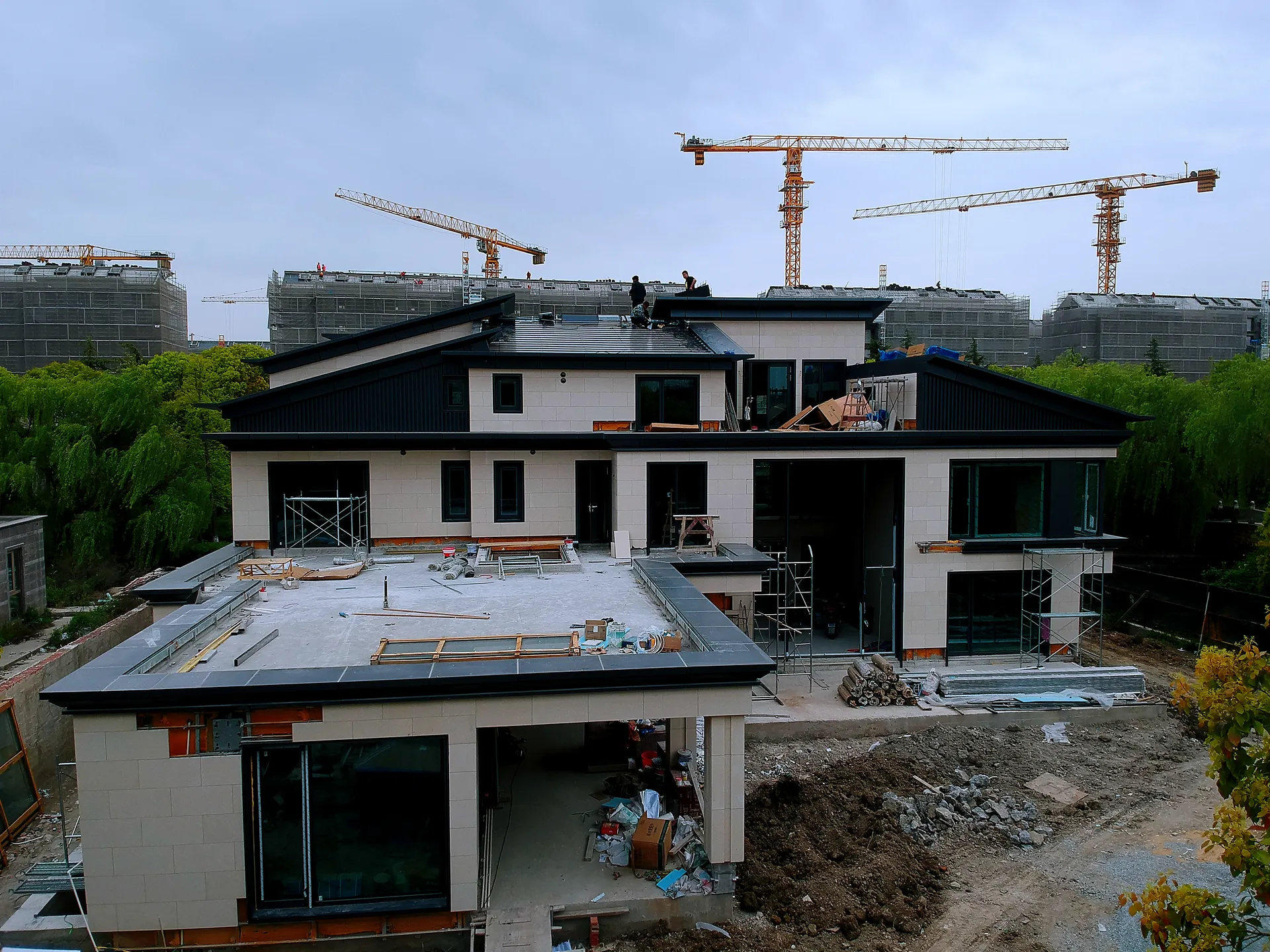 Front elevation of the custom mansion during construction, showcasing the expansive and sleek modern solar roof.