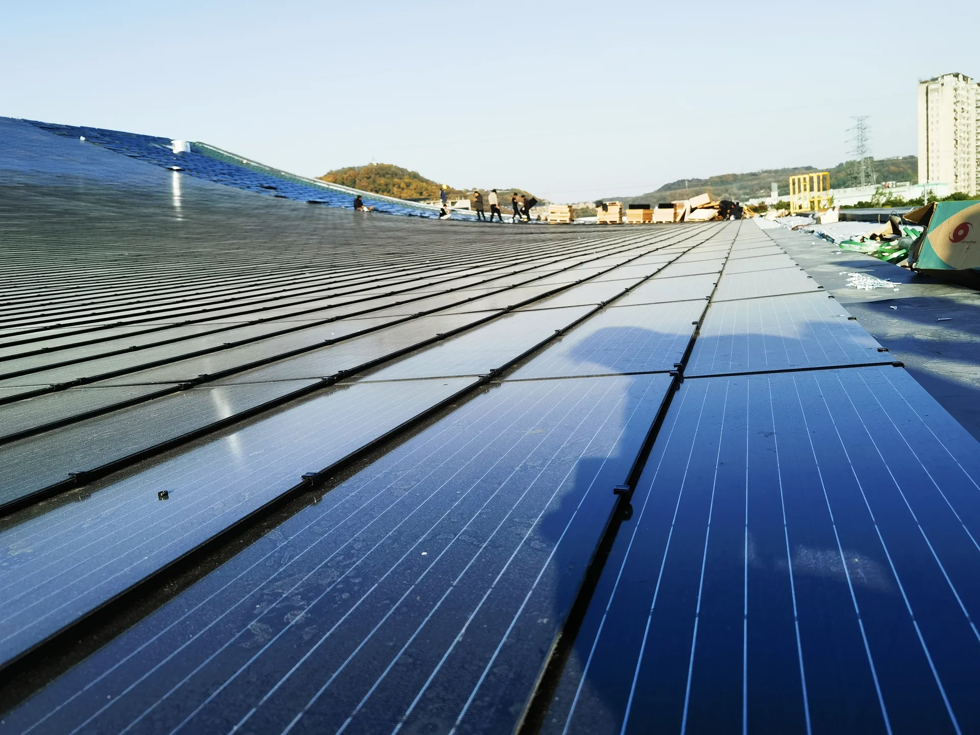 Long perspective shot showing the precise alignment of solar panels across the vast industrial roof expanse.