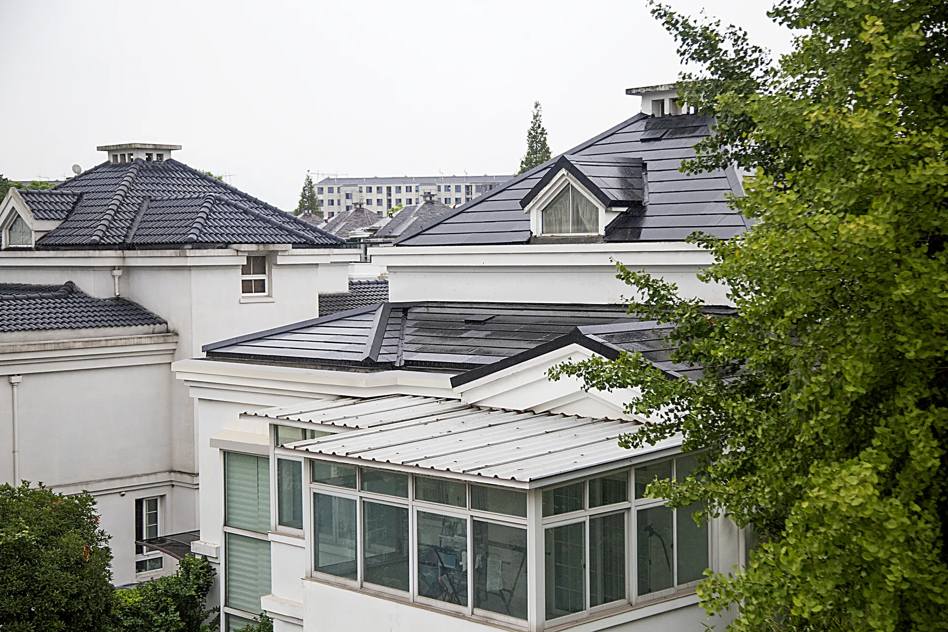 Wide exterior view of a white luxury villa in Shanghai, contrasting its modern invisible solar roof with neighboring traditional tiles.