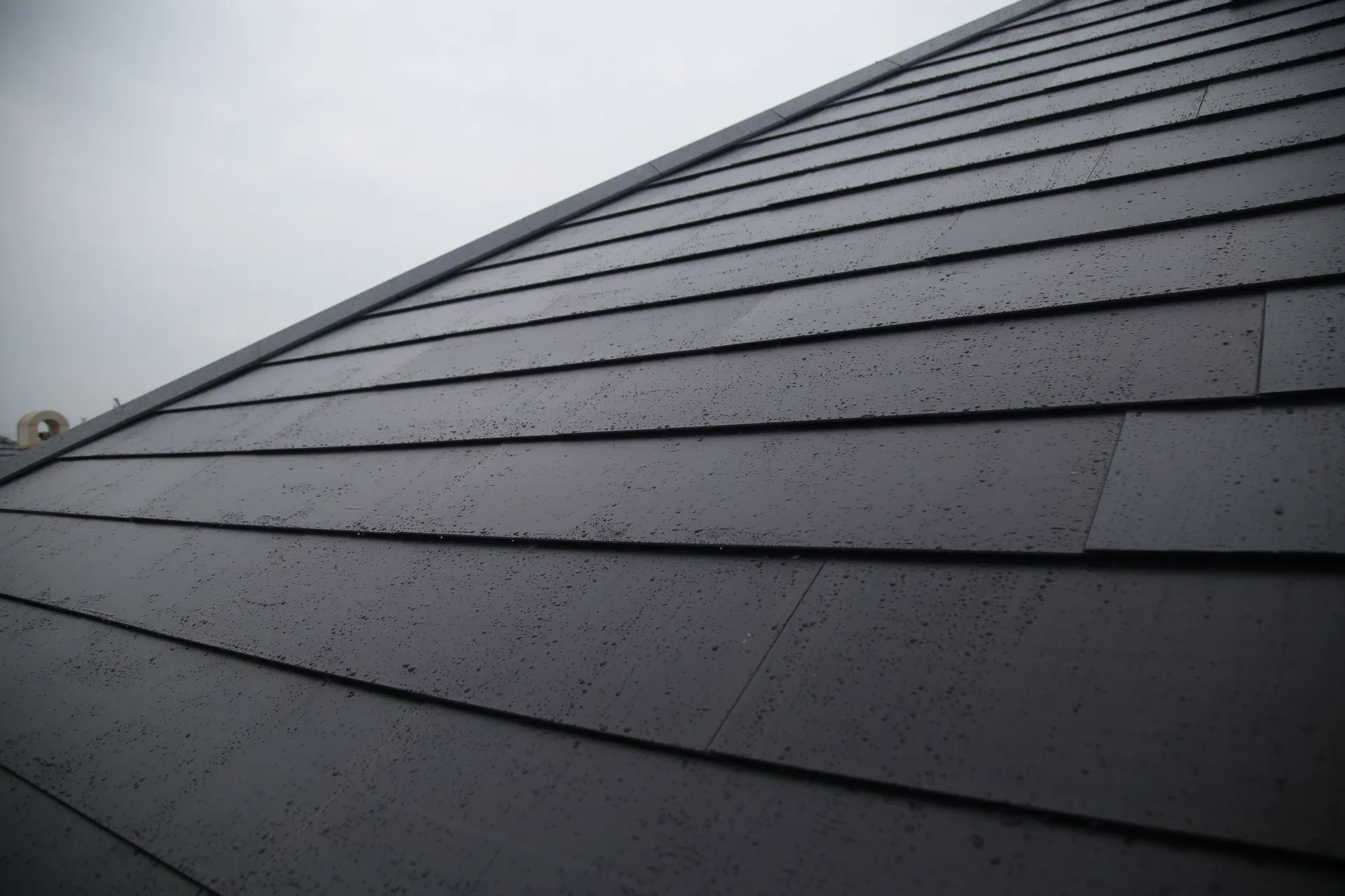 Close-up of the Lumina Slate solar roof surface with rain droplets, showcasing its premium waterproof texture and sleek finish.