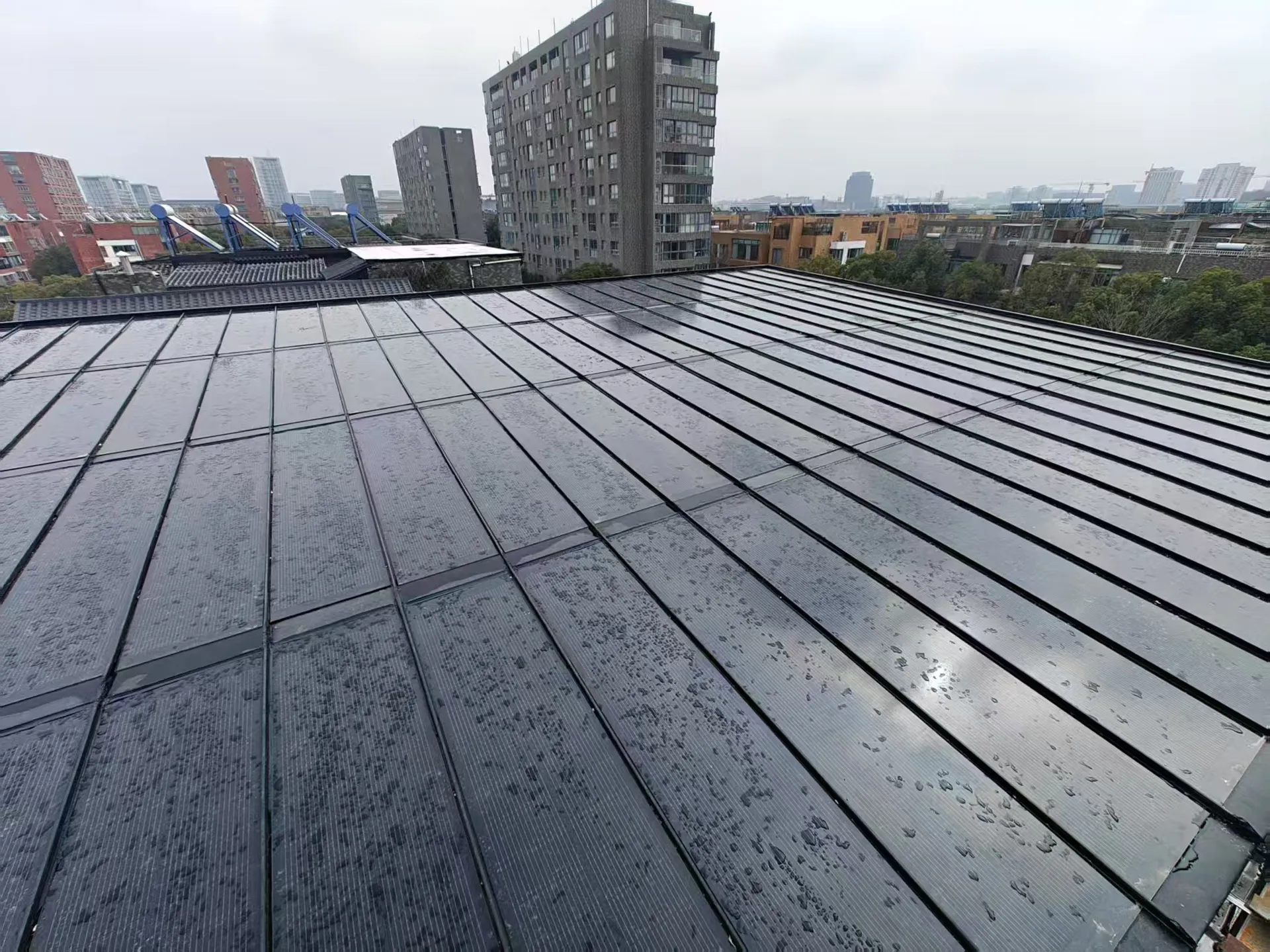 Wet surface of the Storm Guard flat roof BIPV system, demonstrating excellent drainage and waterproofing on a low-slope structure.