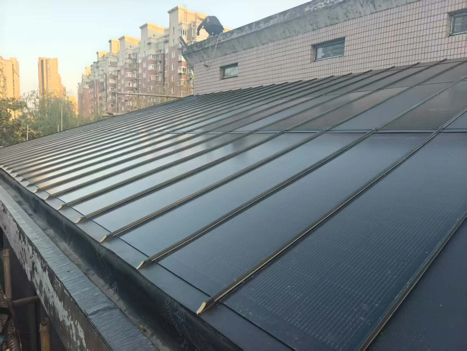 Wet surface of the Storm Guard flat roof BIPV system, demonstrating excellent drainage and waterproofing on a low-slope structure.