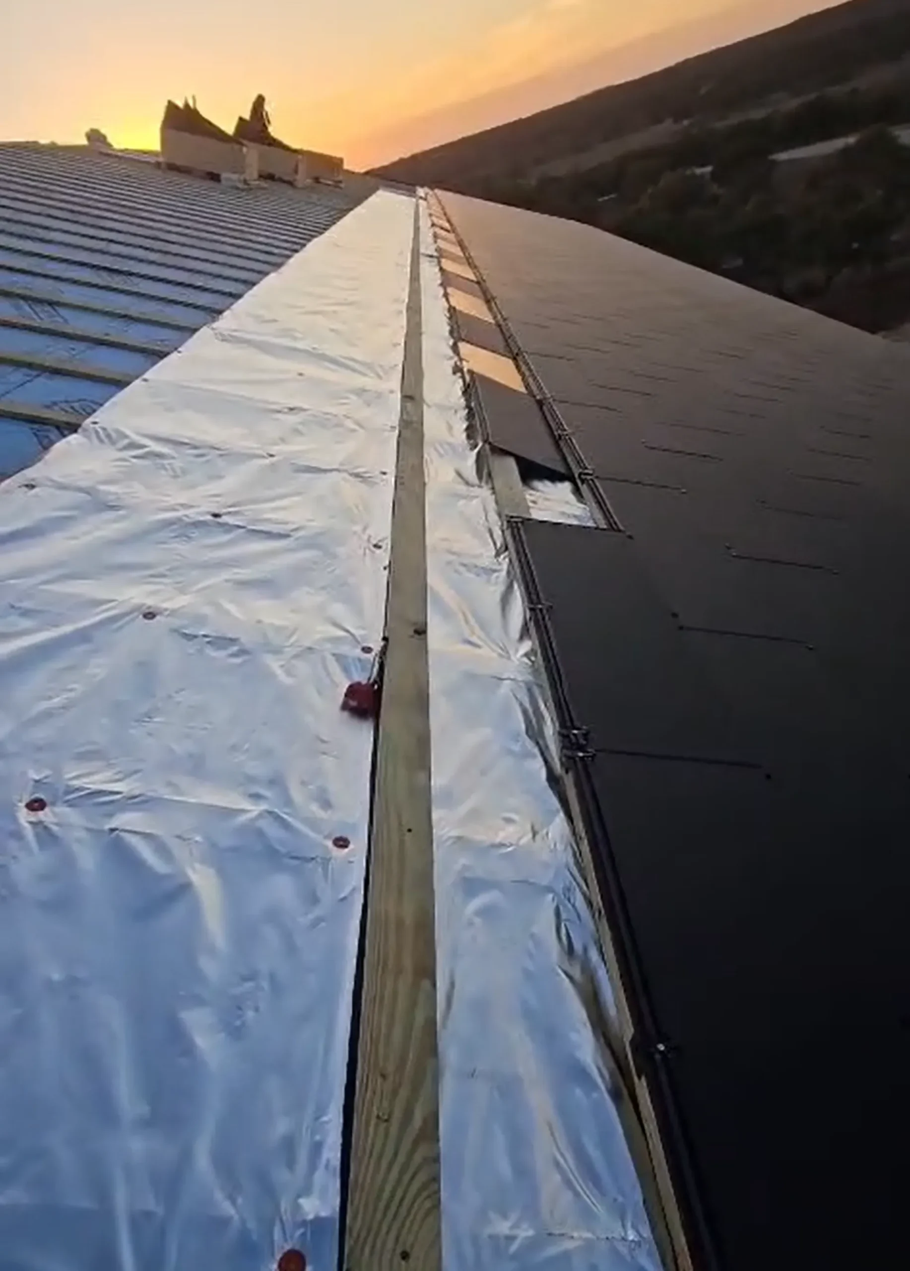 Aerial look at the construction phase where the wooden framing meets the newly installed dark solar tiles.